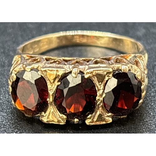 102 - A vintage 9ct gold gypsy style garnet set trilogy ring. High mount and shoulders with pierced work h... 