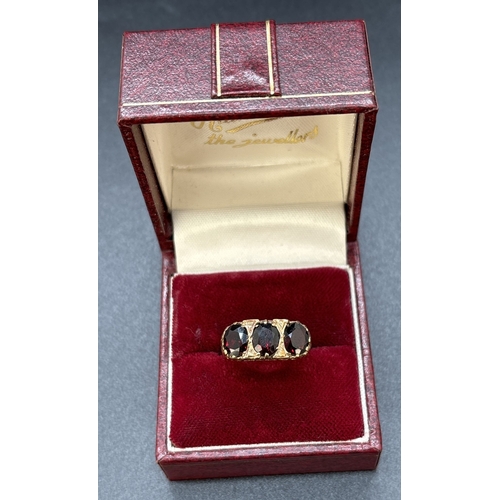 102 - A vintage 9ct gold gypsy style garnet set trilogy ring. High mount and shoulders with pierced work h... 