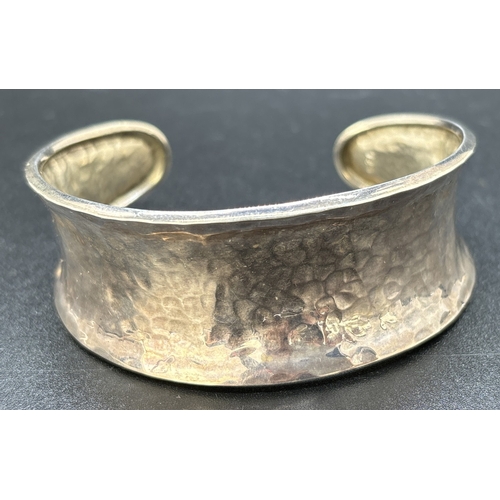 91 - A modern design silver cuff bangle with hammered effect decoration. Silver marks to inside of bangle... 