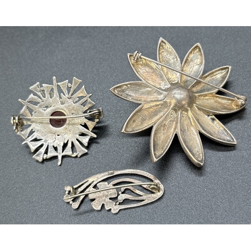 47 - 3 silver brooches. A small floral design brooch, a large flower with central faux pearl and marcasit... 