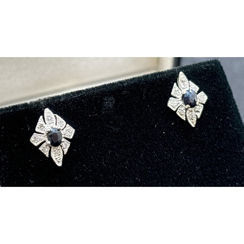 1042 - A pair of unmarked 9ct gold, diamond and sapphire stud earrings. Central oval cut sapphires surround... 