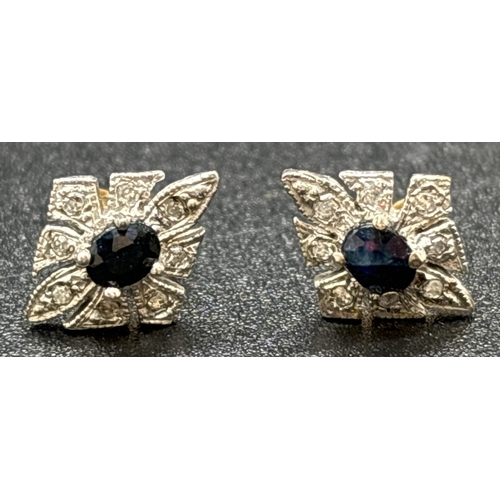 1042 - A pair of unmarked 9ct gold, diamond and sapphire stud earrings. Central oval cut sapphires surround... 