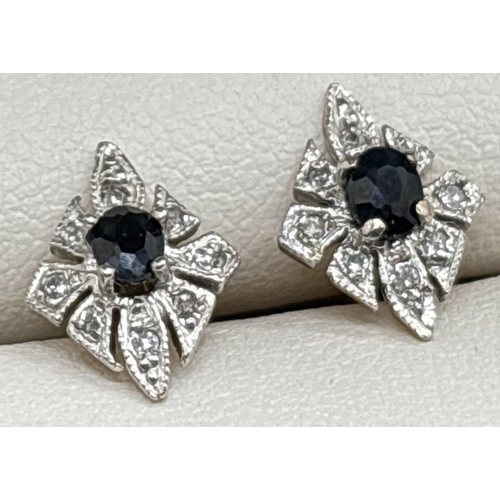 1042 - A pair of unmarked 9ct gold, diamond and sapphire stud earrings. Central oval cut sapphires surround... 