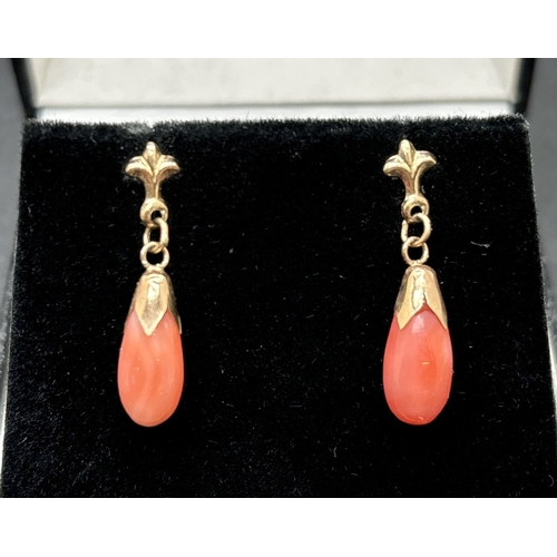 1048 - A pair of 9ct gold coral drop earrings. Each earring comprises a teardop of peachy coloured coral wi... 