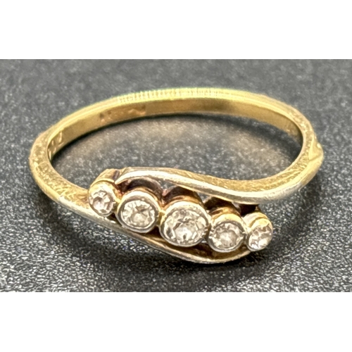 1044 - An 18ct yellow gold Art Deco diamond ring in a crossover design. 5 graduating sized bezel set round ... 