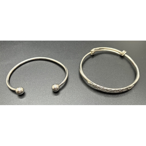 1064 - 2 silver bangles. A plain cuff bangle with ball ends and an adjustable bangle with peacock detail to... 