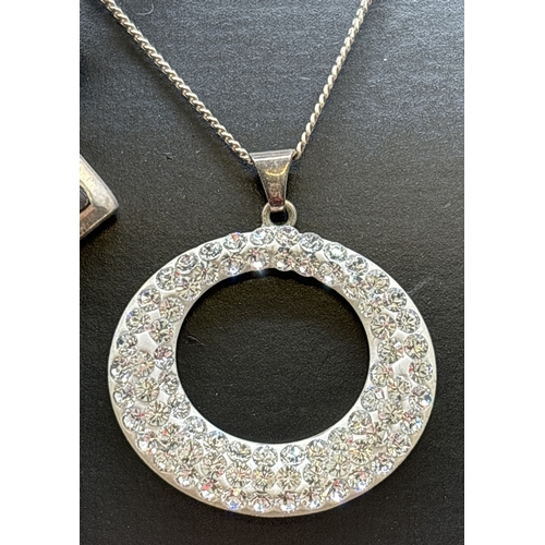 1068 - 3 silver pendant necklaces. A modern design oval pendant set with small clear crystals, on an 18