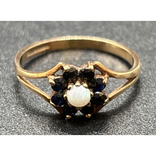 1074 - A vintage 9ct gold flower style cluster ring. A central round cut opal surrounded by 8 sapphires. Sp... 