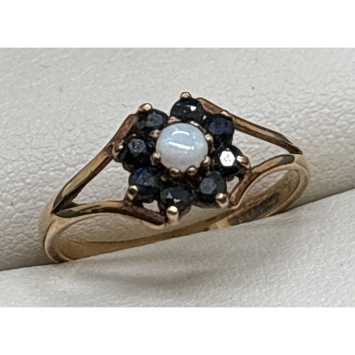 1074 - A vintage 9ct gold flower style cluster ring. A central round cut opal surrounded by 8 sapphires. Sp... 