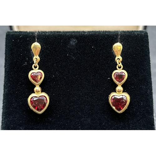 1075 - A pair of unmarked gold double heart drop earrings set with garnets. With butterfly backs. Test as 9... 