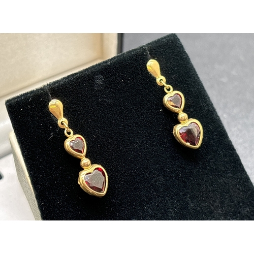 1075 - A pair of unmarked gold double heart drop earrings set with garnets. With butterfly backs. Test as 9... 