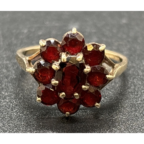 1053 - A vintage 9ct gold garnet cluster ring. Central oval cut garnet surrounded by 8 round cut garnets. G... 