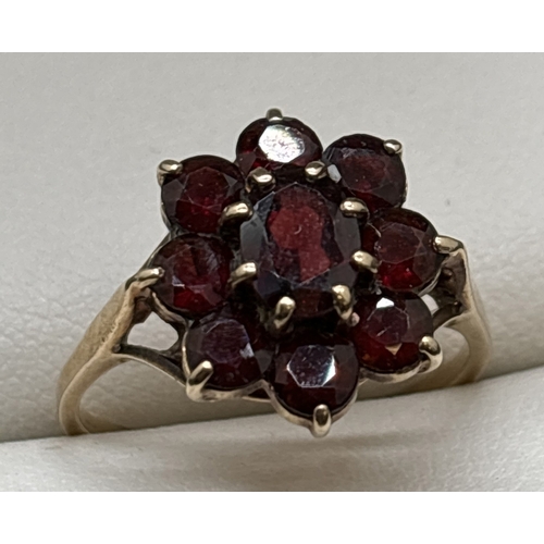 1053 - A vintage 9ct gold garnet cluster ring. Central oval cut garnet surrounded by 8 round cut garnets. G... 