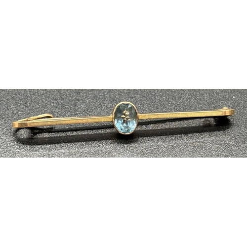 1087 - A vintage 9ct gold bar brooch with milgrain set central oval cut blue topaz. Gold mark on side of br... 