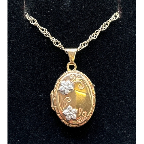 1088 - A small oval 9ct gold locket with white gold flower decoration to front, on a 16