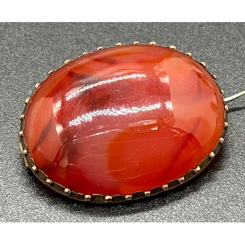 1107 - A late Victorian oval shaped carnelian brooch with unmarked gold mount (tests as 14ct). Hinged pin w... 