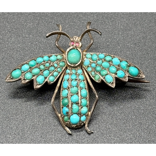 1121 - An antique brooch modelled as a winged insect with pave set turquoise cabochons and small ruby eyes.... 