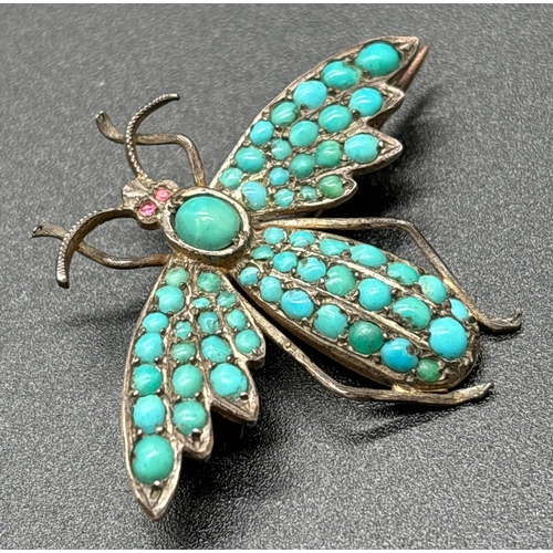 1121 - An antique brooch modelled as a winged insect with pave set turquoise cabochons and small ruby eyes.... 