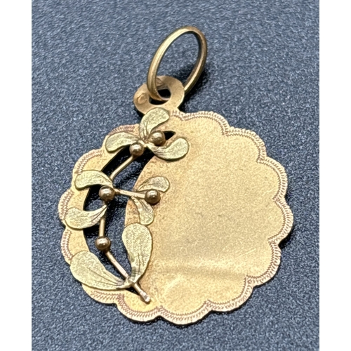 1122 - A French 18ct gold pendant with scallop edges and mistletoe decoration. Eagles head and other indist... 