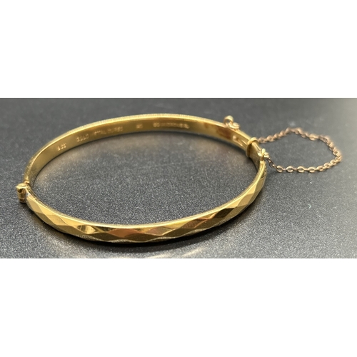 1124 - A vintage 9ct gold metal core bangle with diamond pattern throughout, push clasp and safety chain. G... 