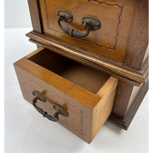 1394 - An Edwardian table top 2 draw cabinet with inlaid detail and metal drop handles. Raised on 4 wooden ... 