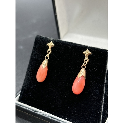 1048 - A pair of 9ct gold coral drop earrings. Each earring comprises a teardop of peachy coloured coral wi... 