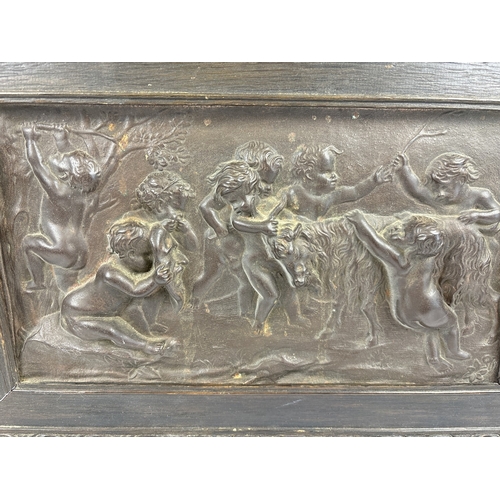 1242 - An antique relief bronze plaque showing cherubs with a goat, mounted in a dark oak frame with carved... 