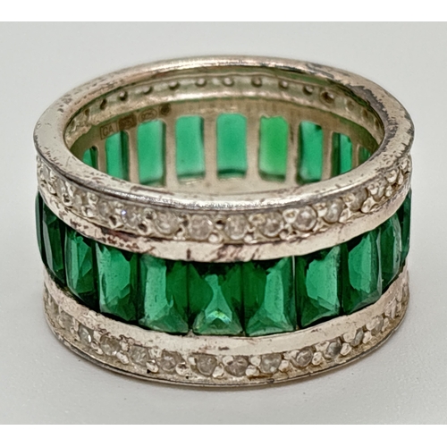 1077 - A 925 silver band style cocktail ring with a central row of baguette cut green stones. With a row of... 