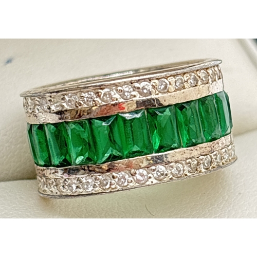 1077 - A 925 silver band style cocktail ring with a central row of baguette cut green stones. With a row of... 