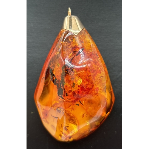 1095 - A large honey amber pendant with natural black and butterscotch inclusions fitted with gold cap and ... 