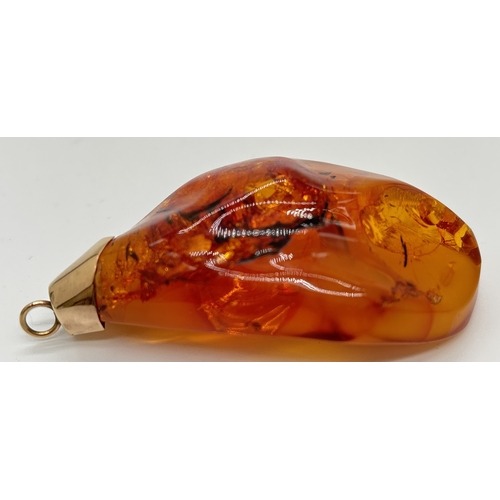 1095 - A large honey amber pendant with natural black and butterscotch inclusions fitted with gold cap and ... 