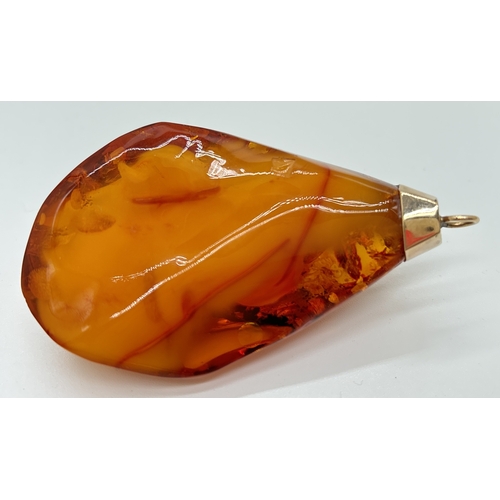 1095 - A large honey amber pendant with natural black and butterscotch inclusions fitted with gold cap and ... 