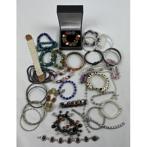 1097 - A collection of modern and vintage bangles and bracelets. Examples include enameled zebra bangle, na... 