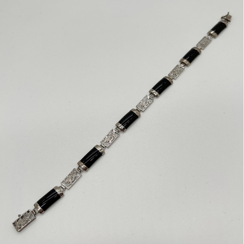 1099 - A silver alternating black onyx and pierced work panel bracelet. Pierced work panels show a dragon d... 