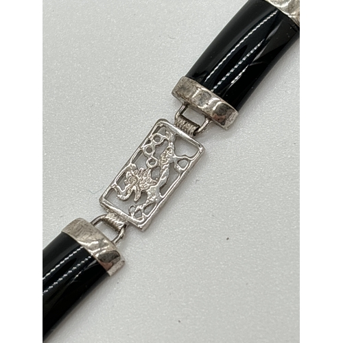 1099 - A silver alternating black onyx and pierced work panel bracelet. Pierced work panels show a dragon d... 