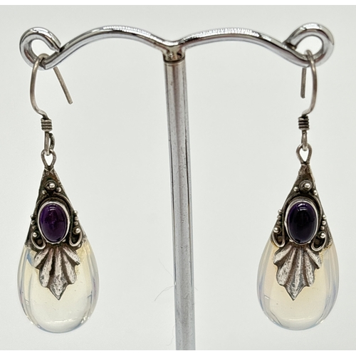 1124 - A pair of silver, moonstone and amethyst drop style earrings with silver scallop and scroll design o... 