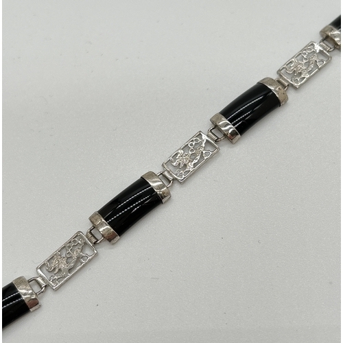 1099 - A silver alternating black onyx and pierced work panel bracelet. Pierced work panels show a dragon d... 