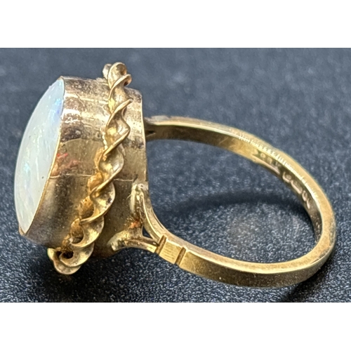 1117 - A vintage 9ct gold large oval cut bezel set opal dress ring with twist design surround. Split should... 