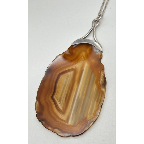 1012 - A large pendant of sliced brown agate with white metal cap and bale, on an 18