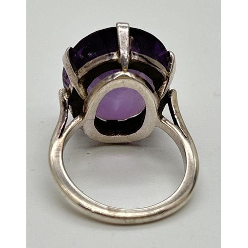 1014 - A large vintage amethyst and white metal cocktail ring with claw set oval cut amethyst, approx. 22 x... 