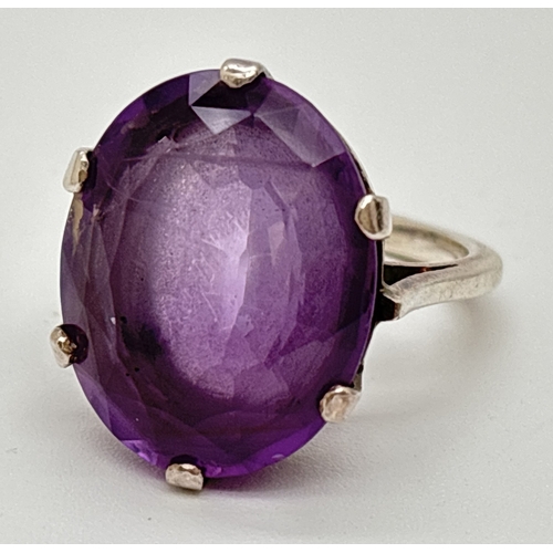 1014 - A large vintage amethyst and white metal cocktail ring with claw set oval cut amethyst, approx. 22 x... 