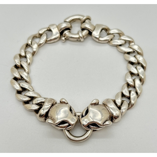 1002 - A 7.5 inch silver curb chain bracelet with 2 Leopards head links. Large spring clasp fastening. Silv... 