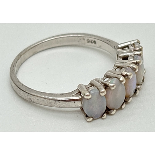 1072 - A silver half eternity style ring set with 5 oval cut white opals. Silver marks to inside of band. S... 