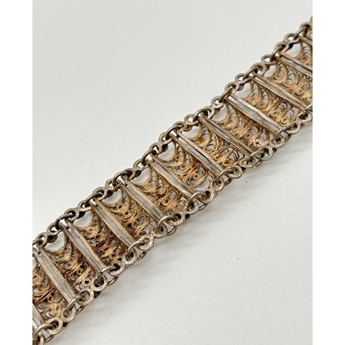 1077 - A vintage white metal filigree panel bracelet with floral decoration and push pin clasp. Approx. 7 i... 