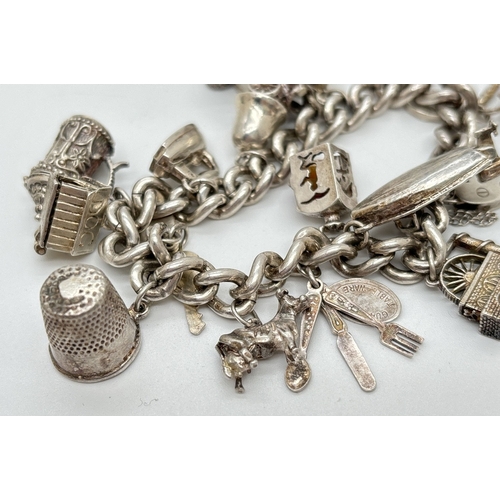 1084 - A vintage silver charm bracelet with safety chain and 15 silver and white metal charms, some with mo... 