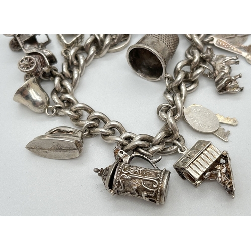 1084 - A vintage silver charm bracelet with safety chain and 15 silver and white metal charms, some with mo... 