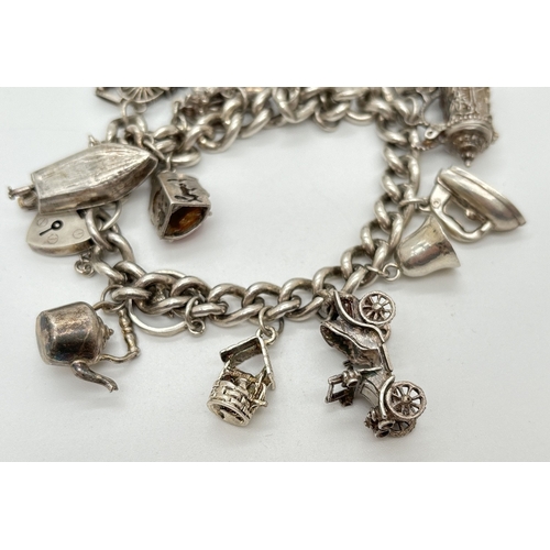 1084 - A vintage silver charm bracelet with safety chain and 15 silver and white metal charms, some with mo... 