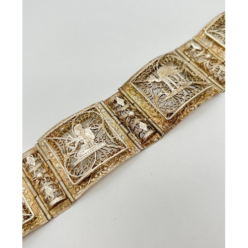 1086 - A vintage white metal 8 panel bracelet with filigree decoration and Egyptian character detail. Alter... 