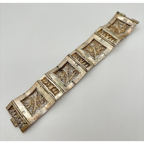 1086 - A vintage white metal 8 panel bracelet with filigree decoration and Egyptian character detail. Alter... 