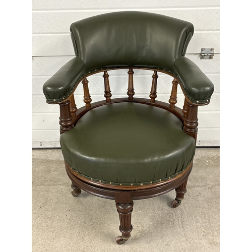 1472 - An antique swivel captains chair with green leather upholstery back, arms and seat. With turned spin... 